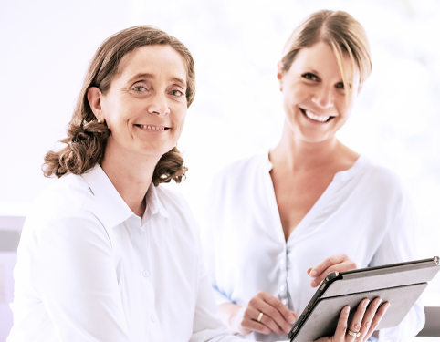 Two female doctors with tablet, conferring. Two female doctors with tablet, conferring.